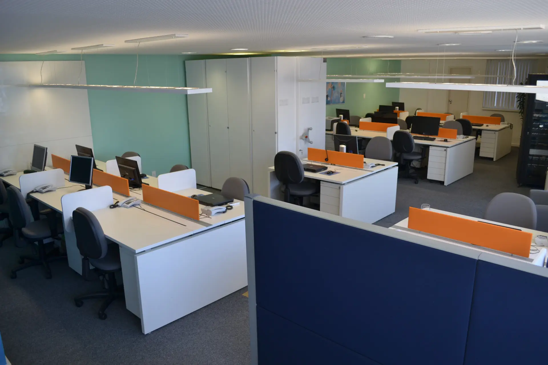 Escritório com estações de trabalho e divisórias coloridas